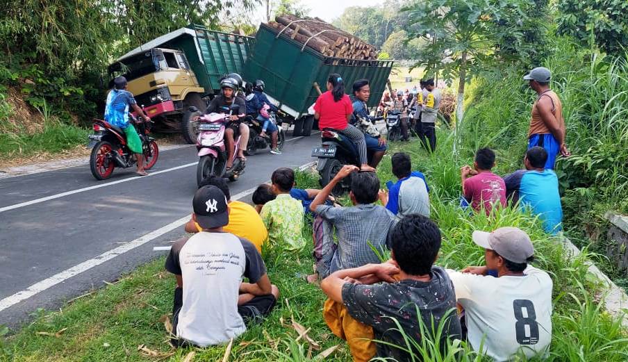 JADI TONTONAN: Warga melihat truk yang mengalami kecelakaan tunggal di jalan tanjakan Dusun Kramat, Desa Sebanen, Kecamatan Kalisat, Jember, Kamis (29/9) sore.