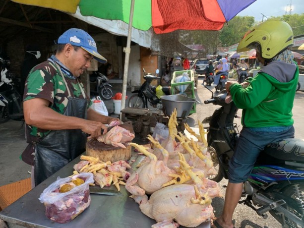 DIPOTONG: Pedagang daging ayam sedang melayani pembeli. Memotong beberapa bagian daging ayam untuk dibawa pulang.