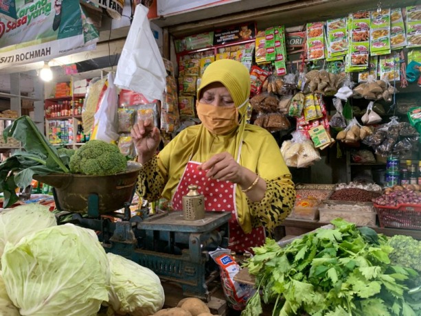 NAIK: Pedagang di pasar Lumajang sedang menimbang barang dagangan pembeli untuk dibawa pulang.