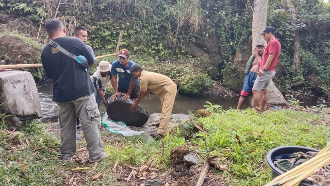 GOTONG ROYONG: Sejumlah juru pelihara dan pegawai Disparbudpora Bondowoso ketika membawa benda megalitikum di tepi sungai.