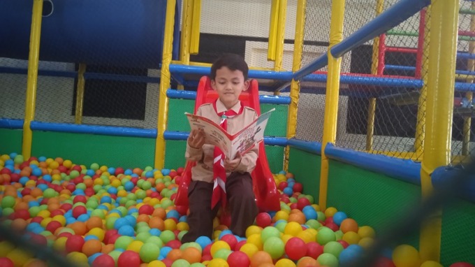 CERIA: Pelajar SD sedang membaca sambil bermain di Perpusda Bondowoso. Ruang baca diiringi hiburan tersebut untuk memantik minat siswa.