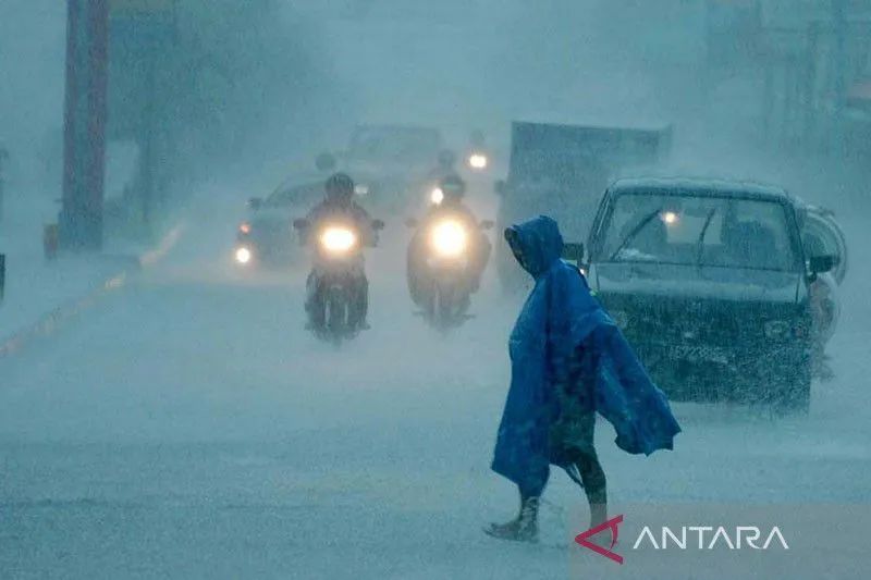Caption Foto :  Seorang warga melintas diantara pengendara bermotor yang melintasi jalan Laksda Adisucipto saat terjadi hujan yang lebat, di Yogyakarta, Rabu (10/3). 