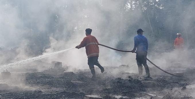 TAK TERSISA: Petugas pemadam kebakaran dari Unit Ambulu sedang memadamkan api sisa-sisa gudang yang terbakar, Minggu (2/10) pagi.