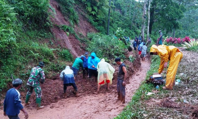 GOTONG ROYONG: Warga, karyawan kebun, serta personel TNI dan Polri bahu-membahu membersihkan material longsoran yang menutup jalur menuju wisata Gunung Gambir, Sumberbaru, Jember, Rabu (12/10) sore.
