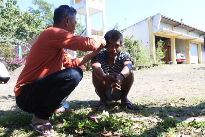 MERAWAT: Kepala UPT Liposos Dinsos Jember Roni Efendi sedang mencukur rambut ODGJ di halaman Liposos Jember.