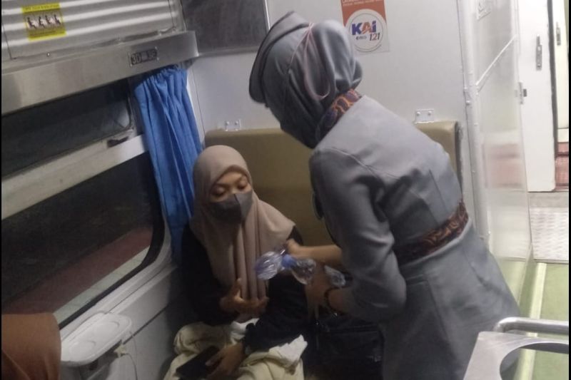 Pramugari kereta api memberikan air mineral kepada penumpang KA Tawangalun yang tertahan di Stasiun Kalisat akibat banjir di Kalibaru, Kamis malam (3/11/2022).