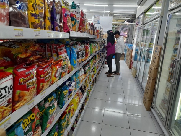 MENINGKAT: Salah seorang pegawai minimarket melayani para pembeli.