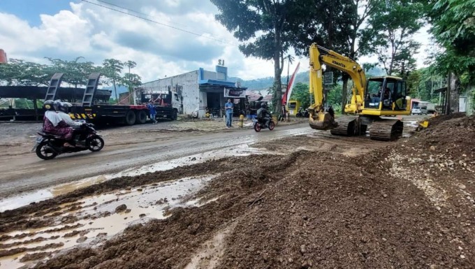BERSIHKAN LUMPUR: Alat berat terlihat sedang membersihkan lumpur bercampur batu yang menutupi separuh jalan nasional di Dusun Barurejo, Kalibaru Manis, Kalibaru, Banyuwangi, Jumat (4/11).