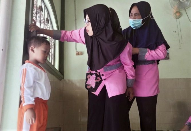 KAWAL PERTUMBUHAN: Yayuk Dwi R, bersama kader posyandu yang lain, mengukur tinggi badan seorang anak di posyandu. Pengukuran dan penimbangan badan dilakukan rutin setiap sebulan sekali untuk memantau tumbuh kembang anak.