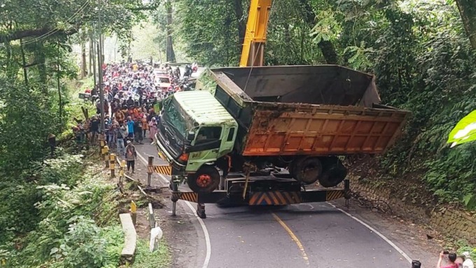 SEBABKAN MACET: Proses pengangkatan badan truk yang terperosok di jurang. Petugas mendatangkan alat katrol dari Surabaya untuk evakuasi kendaraan pengangkut pasir tersebut.