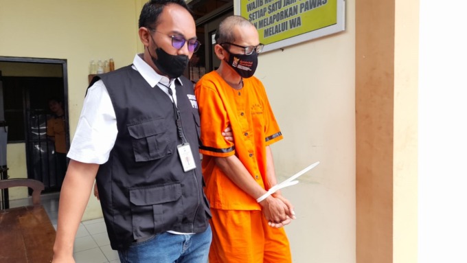 TAK BERKUTIK: Tersangka kasus pencabulan terhadap anak tirinya saat dibawa anggota Polres Bondowoso. 