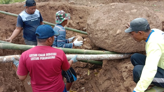NILAI SEJARAH: Masyarakat bersama juru pelihara saat melakukan evakuasi batu megalitikum yang baru ditemukan.