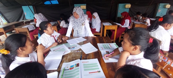 PAKAI TENDA: Uswatun Hasanah, guru honorer SDN Gelang 07 dengan sabar mengajar siswa di halaman sekolah.