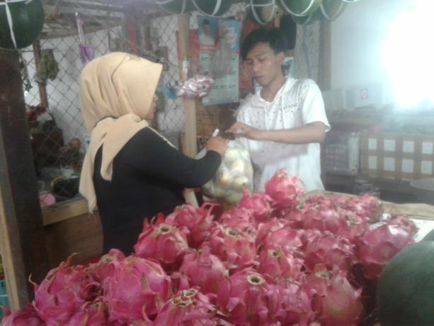 LAKU KERAS: Salah seorang pedagang buah naga di Pasar Tanjung ketika melayani pembeli. Penjualannya selama momen Imlek pun meningkat.