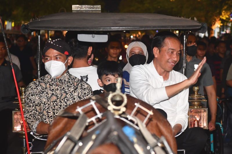 Presiden RI Joko Widodo (kanan) menyapa masyarakat saat berkeliling menumpangi andong bersama keluarganya di kawasan Jalan Malioboro, Yogyakarta, Sabtu (7/1/2023)..