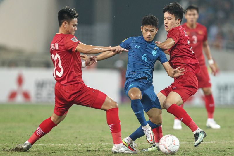Gelandang tim nasional Thailand Sarach Yooyen (tengah) berebut bola dengan pemain Vietnam pada laga leg pertama final Piala AFF 2022 di Stadion Nasional My Dinh, Hanoi, Vietnam, yang berakhir imbang 2-2, Jumat (13/1/2023).