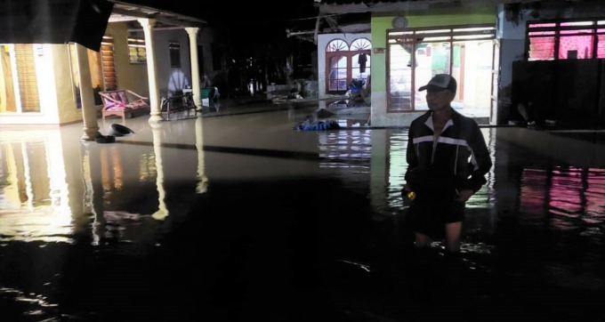 SEPERTI KOLAM: Salah seorang warga memeriksa kedalaman banjir yang merendam halaman rumahnya di Dusun Curahbuntu, Desa/Kecamatan Jenggawah, Jember, Senin (16/1) malam.