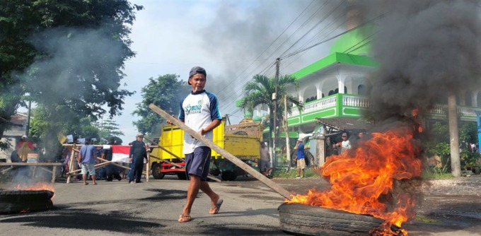 BENTUK PROTES: Warga membakar ban dan memasang plang bambu di jalur provinsi dekat Masjid Arrahman, Desa Kasiyan Timur, Kecamatan Puger, Jember, Selasa (17/1).