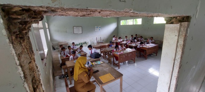 BERTAHAN DARI KEADAAN: Umi, salah seorang guru SDN Curahtakir 03 saat mengajar siswa kelas 1 dan 2. Kegiatan belajar siswa dua kelas itu digabung menjadi satu ruangan.