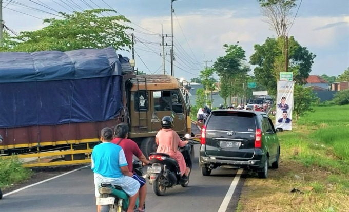 TERHAMBAT: para pengguna yang melintas di Jalan M Yamin, Tegal Besar, Kaliwates, Jember, terganggu dengan adanya truk Fuso yang terperosok dan menghalangi jalan.