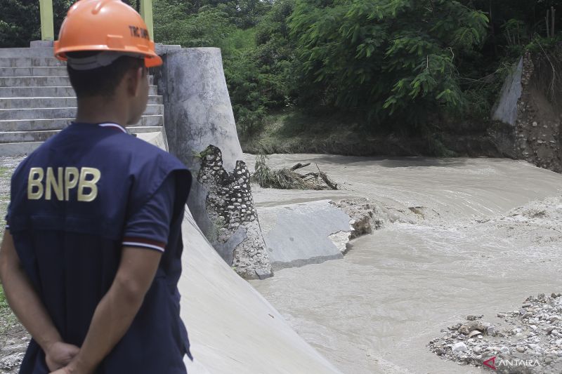 Seorang petugas Badan Penangulanggan Bencana (BNPB) memantau pintu air bendungan Oesao yang jebol akibat cuaca ekstrem berupa hujan yang terjadi di daerah itu Minggu (5/2/2023).