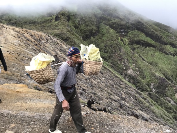 BELUM SEPADAN: Seorang penambang belerang di Kawah Ijen saat memikul hasil tambangnya. Kini, pekerjaan yang cukup ekstrem itu tidak sepadan dengan harga pasaran belerang.