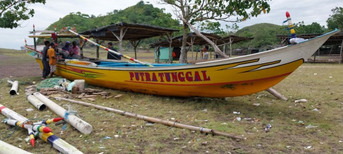 PERBAIKI JUKUNG: Salah satu nelayan asal Puger ketika sedang memperbaiki jukungnya, seusai terhempas gelombang besar. Beruntung, seluruh nelayan selamat.