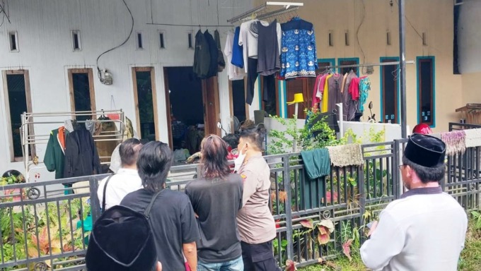 BELUM DIEVAKUASI: Warga bersama petugas kepolisian mendatangi rumah kontrakan. Di rumah ini warga menemukan sesosok mayat yang meninggal dan sudah mengeluarkan bau tak sedap. (Foto: Jumai/Radar Jember)
