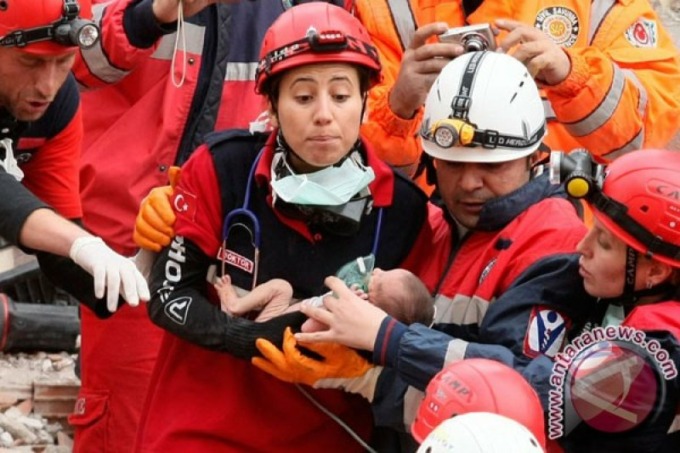 Regu penyelamat mengevakuasi bayi dari reruntuhan gedung di Ercis, dekat Van, Turki, Selasa (25/10). Bayi berumur 14 hari dievakuasi dalam keadaan selamat dari reruntuhan gedung 46 jam setelah gempa bumi menggoncang Turki tenggara, kata pewarta televisi R