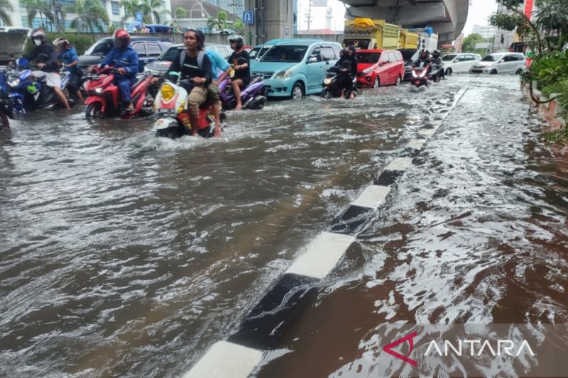 Sejumlah pengendara motor menerobos banjir di jalan protokol Jalan Andi Pangeran Pettarani yang terlihat macet parah saat tergenang air di Makassar, Sulawesi Selatan, Senin (13/2/2023).