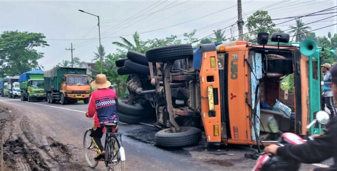 HAMBAT JALAN: Kondisi truk pengangkut pasir yang terguling di jalan raya Dusun Krajan, Desa Bagorejo, Kecamatan Gumukmas, Jember, Jumat (3/2) pagi.