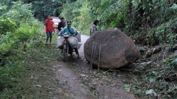TAK BISA LEWAT: Material batu besar yang terbawa longsoran tanah di Desa Mulyorejo, Kecamatan Silo, Jember, Minggu (12/2) siang. Hingga sore tadi, batu tersebut belum bisa diangkat dan menunggu bantuan alat berat.