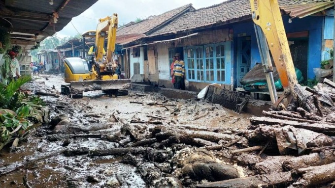 KERJA EKSTRA: Alat berat membersihkan perkampungan yang terdampak banjir bandang di Bondowoso. Kurangnya alat berat mengakibatkan penanganan pascabencana berjalan lambat.