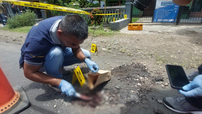 KUMPULKAN BUKTI: Tim Inafis Polres Jember mengambil sampel ceceran darah di lokasi pembacokan, depan Kantor Desa Pringgowirawan, Kecamatan Sumberbaru, kemarin (22/2). (Foto: Jumai/Radar Jember)
