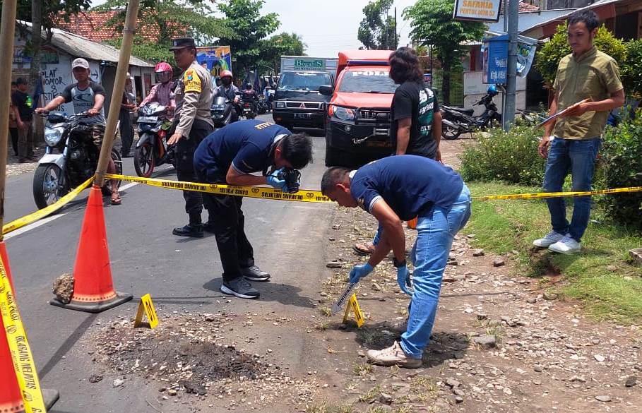 CARI PETUNJUK: Tim Inafis Polres Jember mengambil ceceran darah korban di lokasi pembacokan, depan Kantor Desa Pringgowirawan, Kecamatan Sumberbaru, Rabu (22/2). Hingga kini, polisi masih memburu pelaku penganiayaan yang menyebabkan korban tewas.