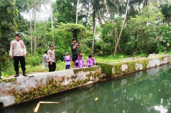DIDUGA DEPRESI: Personel Polsek Gumukmas mendatangi lokasi kolam di Desa Tembokrejo, tempat pria menceburkan diri dan ditemukan meninggal. (Foto: Polsek Gumukmas untuk Radar Jember).