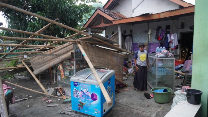 TETAP SABAR : Siti Maimunah membersikah warungnya yang roboh akibat dihempas angin puting beliung, di halaman rumahnya.