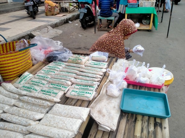 MEMBUNGKUS: Pedagang tahu tempe di pasar sore Pasar Tanjung melayani pembeli tahu. Saat ini ukuran tahu dan tempe mulai mengecil, karena harga kedelai impor mengalami kenaikan.