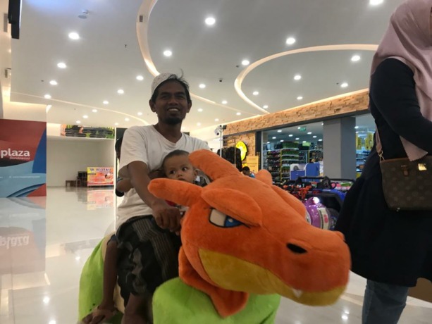 BAHAGIA: Salah seorang warga tengah menikmati wahana bermain di Mal Citiplaza Bondowoso. Padahal mainan itu diperuntukkan bagi anak. (Foto: Ahmad Ma