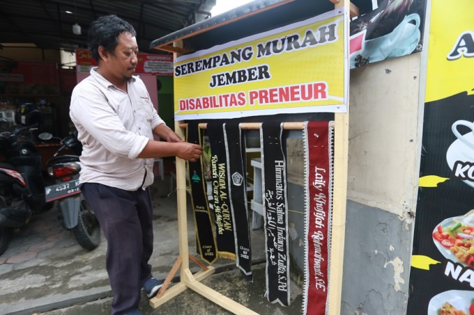 BUAT SELEMPANG: Yahya Udin ketika memamerkan produk dagangannya, selempang yang kerap dipakai mahasiswa saat momen wisuda.   