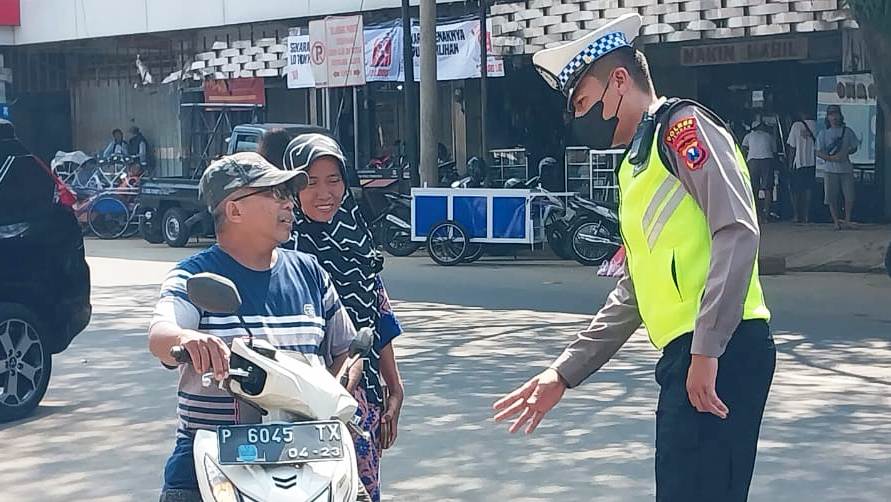 PERSUASIF: Polantas memberi peringatan kepada salah seorang pengendara yang tak mengenakan helm saat berbelanja di Pasar Tanjung. (Foto: Jumai/Radar Jember).