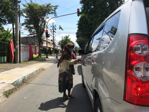 CARI REZEKI: Pengemis di lampu lalu lintas Tamansari saat meminta-minta ke pengemudi mobil. (AHMAD MA’MUN/RADAR IJEN)
