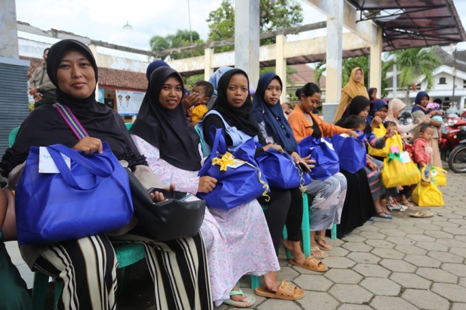SENYUM SENANG: Sejumlah ibu dan anaknya senang saat menerima PMT dari Bupati Jember Hendy Siswanto dalam giat J-Berbagi di Kecamatan Sumbersari, (10/4). Sementara itu, lansia kurang mampu juga mendapatkan bantuan paket sembako.