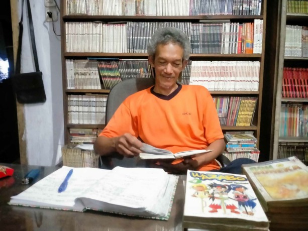 DENGAN GEMBIRA: Tosan Pangudi atau akrab dipanggil Pak Oce memperlihatkan buku komik yang telah dikoleksinya, di Jalan Gatot Subroto nomor 48-18, Kelurahan Kepatihan, Kaliwates.