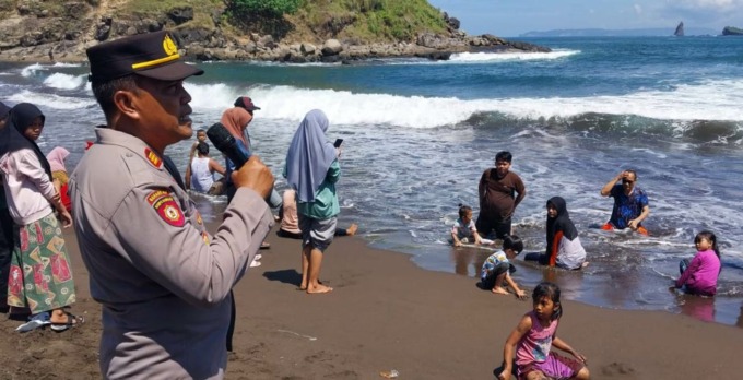 DILARANG MANDI: Kapolsek Ambulu AKP Ma’ruf bersama muspika setempat memberi imbauan kepada wisatawan yang mandi di Pantai Payangan Jember. (FOTO: Jumai/Radar Jember)