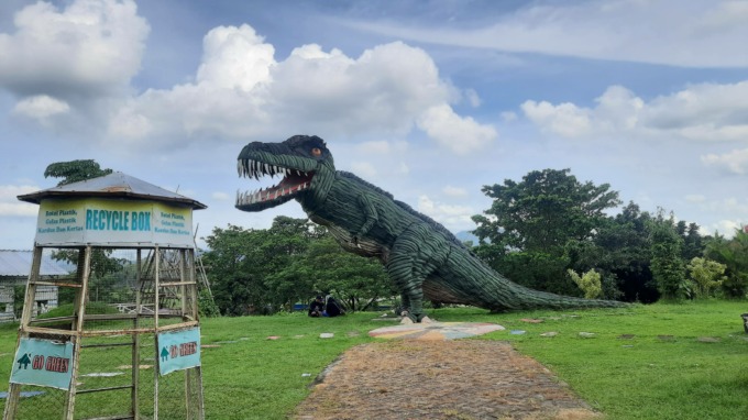 NIKMATI SUASANA: Pengunjung taman TPA Pakusari berfoto ria di depan patung dinosaurus.