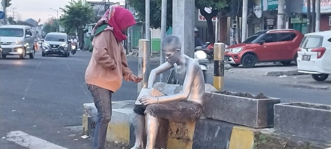 KUMPULKAN UANG: Manusia silver yang mangkal di lampu merah Geladak Kembar terlihat setor uang kepada perempuan.