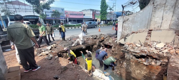 DIKEBUT: Puluhan personel Tim Reaksi Cepat (TRC) DPUBMSDA Jember membersihkan sisa bangunan yang dibongkar dan sampah yang menumpuk di selokan Jalan Gajah Mada, kemarin.