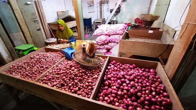 TERUS BEKERJA: Salah satu pedagang mengupas bawang di dalam Pasar Tanjung Jember.