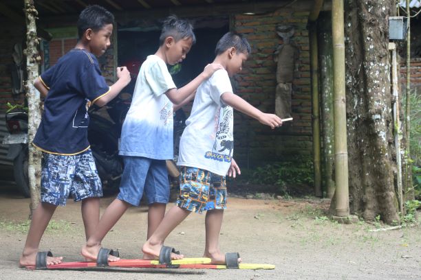 HARUS KOMPAK: Sejumlah anak sedang seru-seruan bermain bakiak. Permainan bakiak ini salah satu permainan tradisional yang masih dimainkan ketika acara seperti HUT RI bulan Agustus. (AZZQAL AZQIYA’/RADAR JEMBER)
